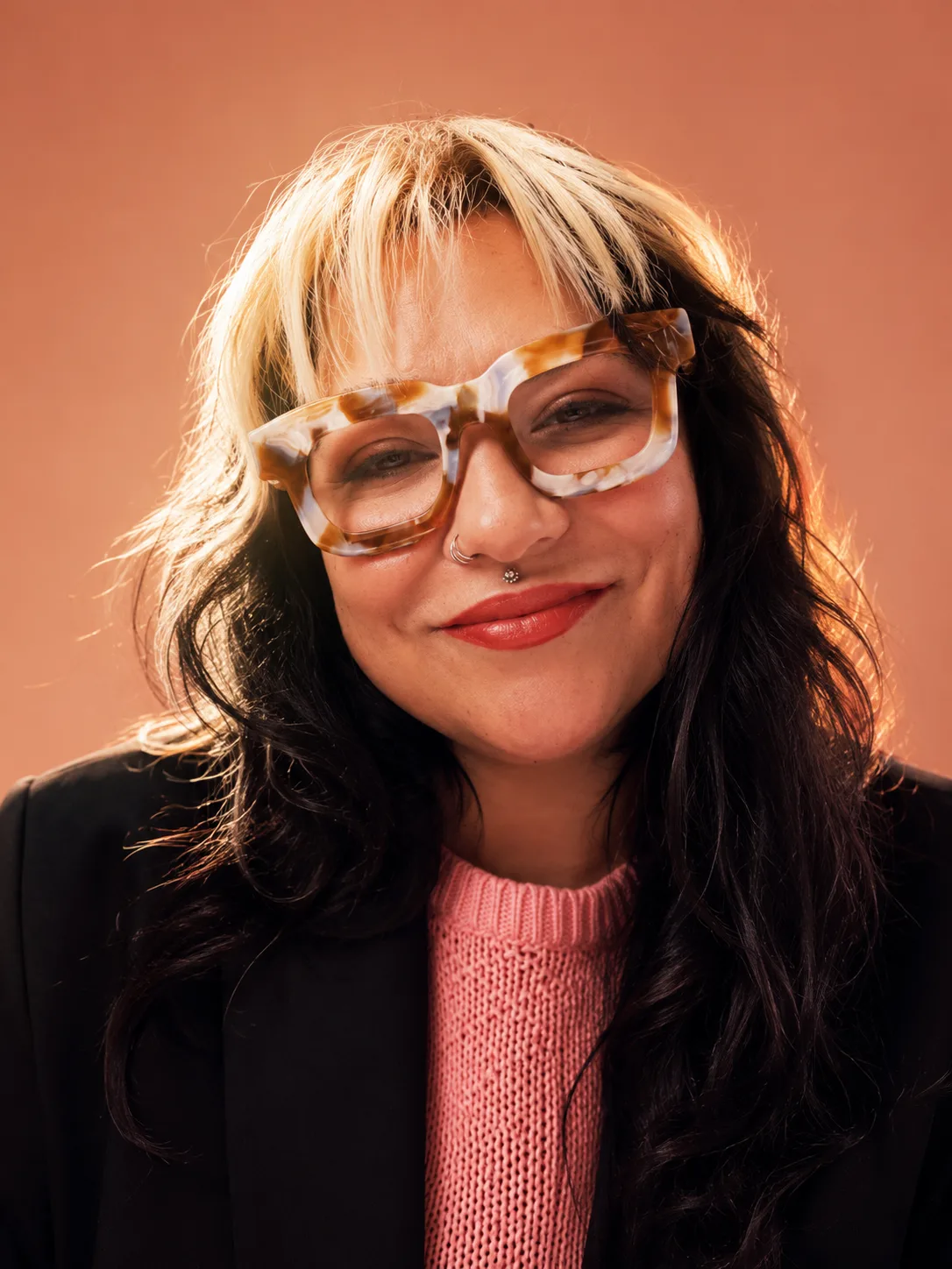 Retrato de Natalia Suárez Jaramillo con gafas, chaqueta negra y suéter rosado.